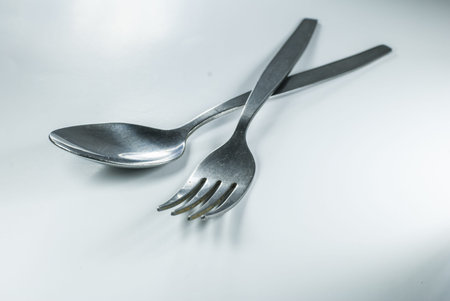 silver spoon and fork in shallow focus close up - isolated on white background