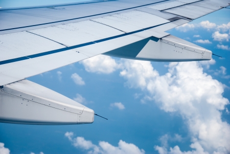 Wing of the plane on sky background - plane wing with cloud patterns - view from the window of a plane of the wing, the sky - View of jet plane wingの写真素材