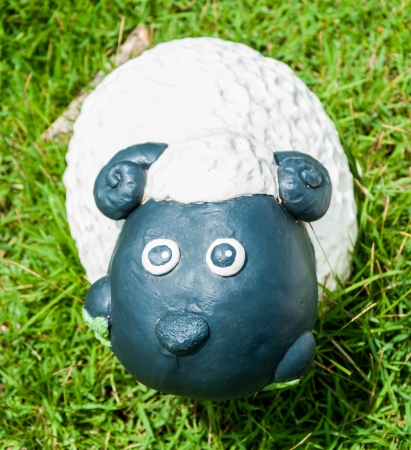 Smile white sheep statue in green grass on daytimeの写真素材