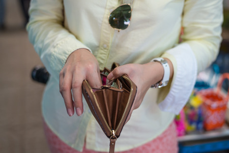 Woman finds money in brown purse or wallet at marketの写真素材