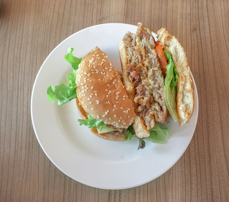 Hamburger with cheese and fresh vegetables in the restaurantの写真素材