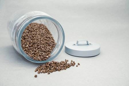 Coffee beans spilling out of a glass jar on white background
