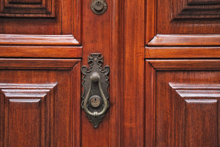 Wooden door with metal handle, detail of a door handle.