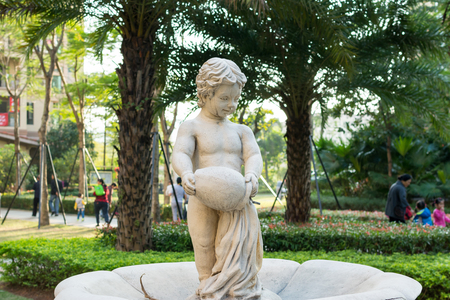 statue of boy holding a jar in the garden.の写真素材