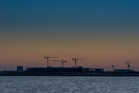 Landscape of sun rising over the construction site with crane in the sea in Dammam, Kingdom of Saudi Arabiaの写真素材