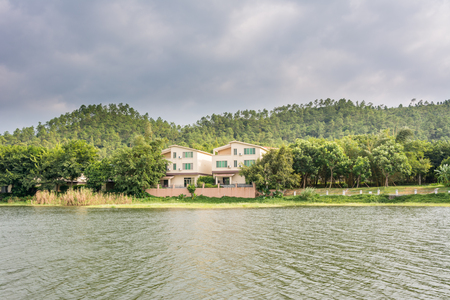 Villa and  hills beside a lake against  cloudy skyin the saltwater warm spring  resort of Yangxi, Yangjiang city, Chinaのeditorial素材
