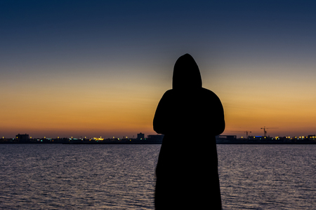 A man with jacket watching sun rising from sea at the corniche park in Dammam, Kingdom Saudi Arabiaの写真素材