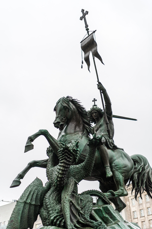 Statue of St George on a horse killing the Dragon. On river site Spree River and facing the old St Nicholas church in Berlin, Germany.のeditorial素材
