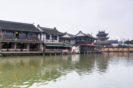 Street view with wooden historic buildings and buddhist temple in Zhujiajiao in a rainy day, an ancient water town in Shanghai, built during Ming and Qing Dynasties of Chinaのeditorial素材