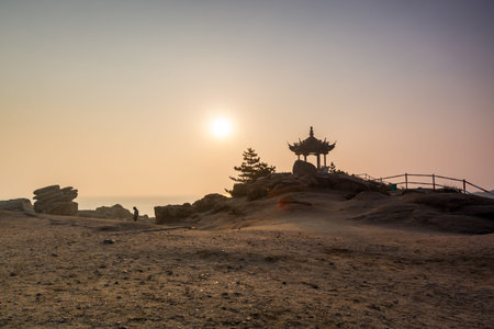 Sunrise over the sea and stone at the seaside of Mount Putuo in the morning, an island southeast of...