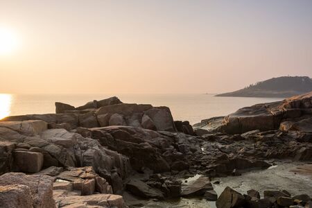 Sunrise over the sea and stone at the seaside of Mount Putuo in the morning, an island southeast of Shanghai in Zhoushan, Zhejiang, China, the bodhimaá¹á¸a of the bodhisattva Guanyin.の写真素材