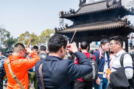 Pilgrim burning incense and praying at Mount Luojia, which lies in the Lotus Sea to the southeast of Putuo Mountain, Zhoushan, Zhejiang, the place where Bodhisattva Guanyin practiced Buddhismのeditorial素材