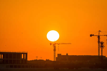 Landscape of sun rising over the construction site with crane in the sea in the morning in Dammam, Kingdom of Saudi Arabiaの写真素材