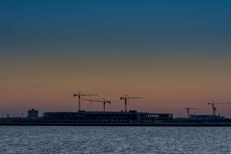Landscape of sun rising over the construction site with crane in the sea in the morning in Dammam, Kingdom of Saudi Arabiaの写真素材
