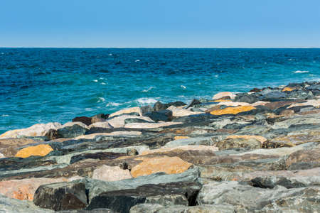 Waves of Persian Gulf splashing the stones of breakwater at the crescent road in the Palm Jumeirah island in Dubai of the United Arab Emirates.の写真素材