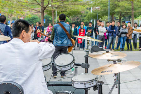 A white suit drummer of a Shenzhen local street band performing at the Central park of Shenhzhen, Guangdong, Chinaのeditorial素材