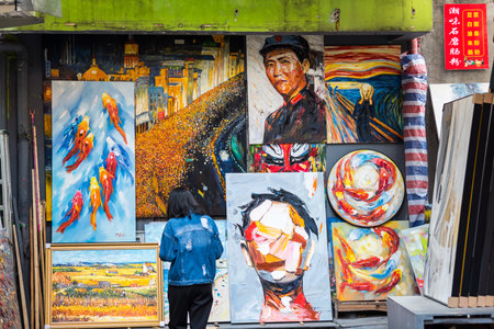 A Chinese woman looking at the oil painting artworks at Dafen Oil Painting village, Shenzhen, China.のeditorial素材