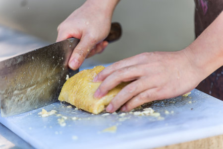 A chinese chef hand using a knife and chopping chicken meat into small pieces.の写真素材