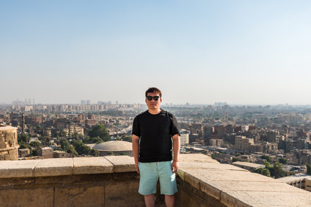 A Chinese tourist standing at the Saladin Citadel of Cairo and Aerial view of Cairo of crowded buildings with dusty skyのeditorial素材