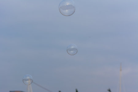 A lot of soap bubbles flying in the park with background of blue sky and sunset on the buildingsの写真素材