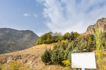 Tochal mountain ridge with rocks and trees in autumn against blue sky, Tehran, Iran. Tochal is a popular recreational region for Tehran's residentsの写真素材