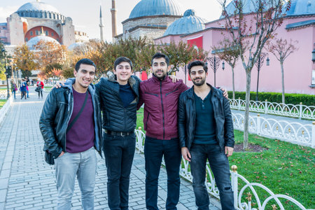 Four turkish men standing in front of Hagia Sophia mosque in the morning against blue sky in autumn in Istanbul, Turkeyのeditorial素材