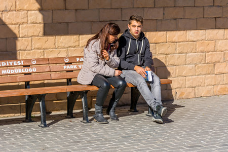 Turkish Tourists sitting on the bench waiting for a ferry to Bosphorus strait in autumn sunny day, Istanbul, Turkeyのeditorial素材