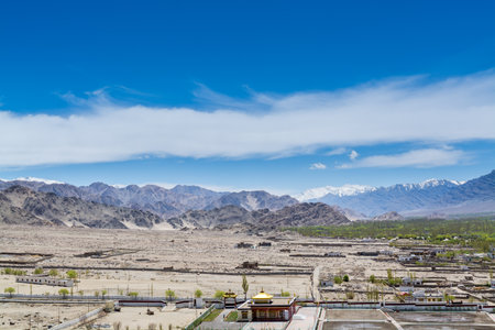 Beautiful landscape with fields, Tibetian buildings, snow mountains, and blue sky, in Ladakh, Kashmir, view from Thiksey Monastery or Thiksey Gompaの写真素材