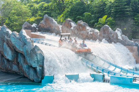 Tourists sitting on boat flushing into water with splash on the track in park of Chimelong Ocean Kingdom, Zhuhai, Chinaのeditorial素材
