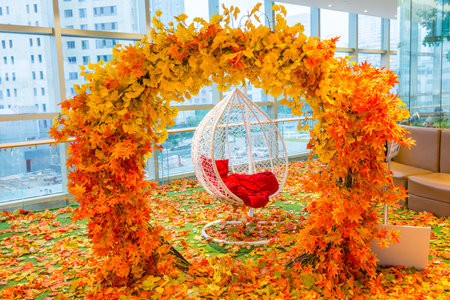 Arch with orange fall foliage with hanging white chairの写真素材