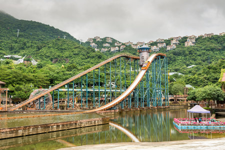 Tourists sitting on boat doing extreme sport water slide with splash on the track in park of Overseas Chinese Town East (OCT East)のeditorial素材