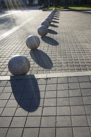 Granite balls on a sidewalk illuminated bright sunの写真素材