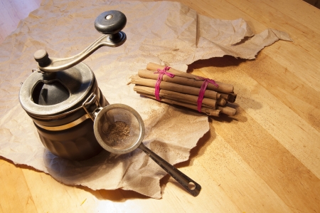 Cinnamon sticks on a wooden table. Near a coffee grinder and packaging papers.の写真素材
