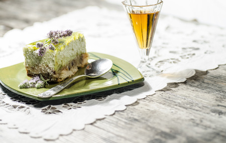 Slice of lime cheesecake decorated with mint flowers and glass of cognac, blurred . From series "Summer desserts"の写真素材