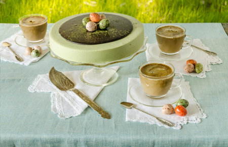 Easter table with tea matcha cheesecake and white coffee on background of green grass. 