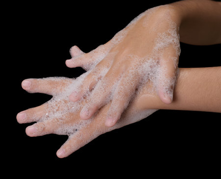 cleaning her hands with soap on black backgroud