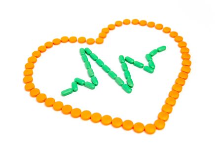 A pulse is by green pills in the orange heart Isolated on white background.の写真素材