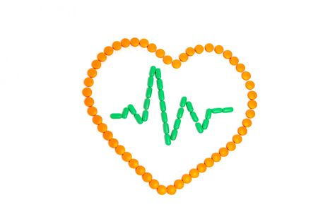 A pulse is by green pills in the orange heart Isolated on white background.の写真素材