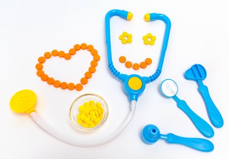 Medicine concept. Childrens toys by doctor. A heart is by orange pills.の写真素材