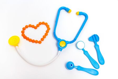 Medicine concept. Childrens toys by doctor. A heart is by orange pills.の写真素材