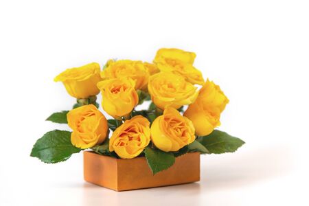 Bouquet of yellow roses is in a small orange box on a white background. Flowers are horizontal close-upの写真素材
