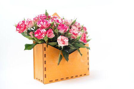 Bouquet of pink roses is in wooden box on a white background. Flowers are horizontal close-upの写真素材