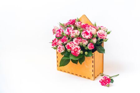 Bouquet of pink roses is in wooden box with a flower near it on a white background. Flowers are horizontal close-up.の写真素材