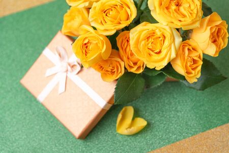 Bouquet of yellow roses is in a small orange box on a green yellow background. Flowers are horizontal close-upの写真素材