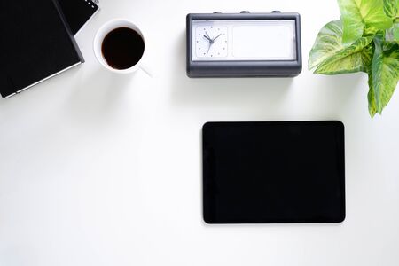 Office desk table with tablet,coffee cup ,pencil ,flower ,notepad on white desk. Top view with copy space.の写真素材