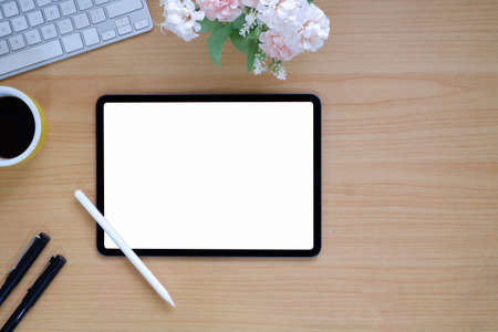 Top view of simple workspace with mock-up tablet, computer device and copy space on wooden table backgroundの写真素材