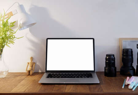 laptop blank screen on wooden table with lamp,plant,lens.の写真素材