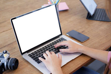 Young woman using black tablet device with white screen. Woman holding tablet, scrolling pages while sitting on the sofa in the living room.の写真素材