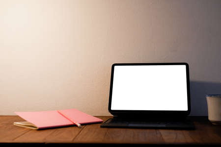 Young woman using black tablet device with white screen. Woman holding tablet, scrolling pages while sitting on the sofa in the living room.の写真素材