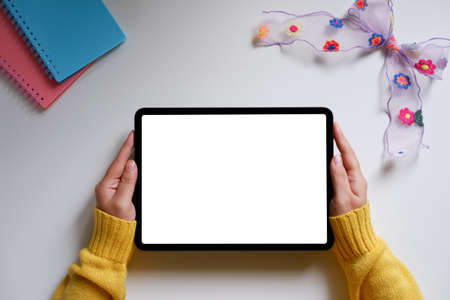 A woman using a blank screen tablet With notebook and ribbonの写真素材